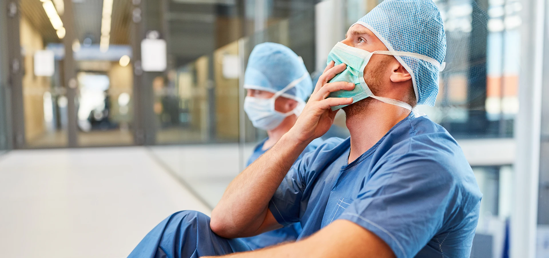 Two doctors sit on the floor of a hospital hall