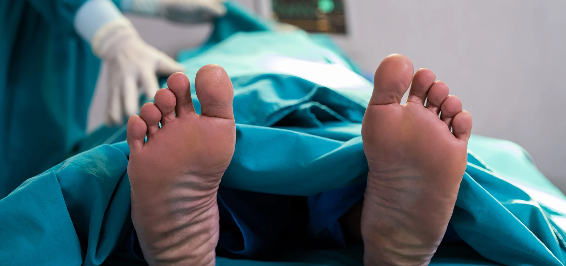 A doctor covers a person in a hospital sheet as we see the feet sticking out the end